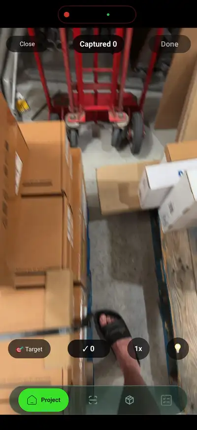 A phone held over a boxed item in a warehouse stockroom, scanning its barcode label — SiteSurvey has read the serial and part numbers off the label and is offering to assign each code to a data point on the asset record